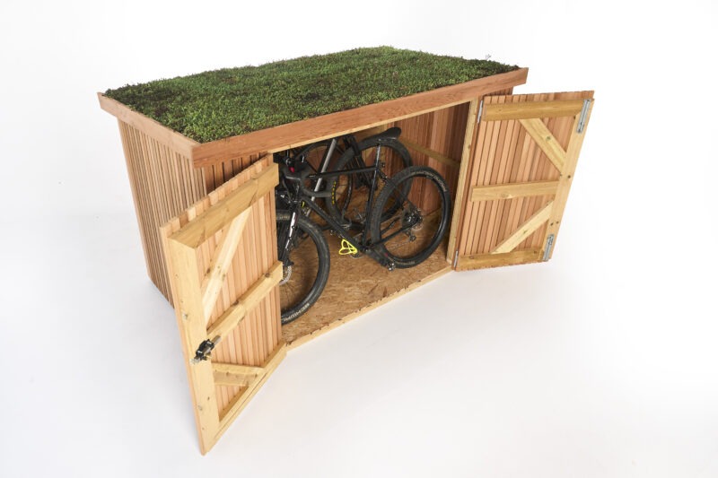 A wooden bike shed with a living roof